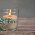Candlelight and evergreens representing shared winter holiday symbolism across Yule, Christmas, and Hanukkah