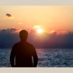 Divine masculine Beltane symbolism with a man standing before the sunset.
